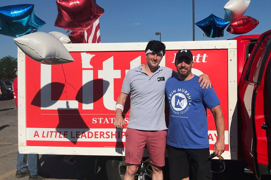 Matt and man standing in front of yard sign on truck
